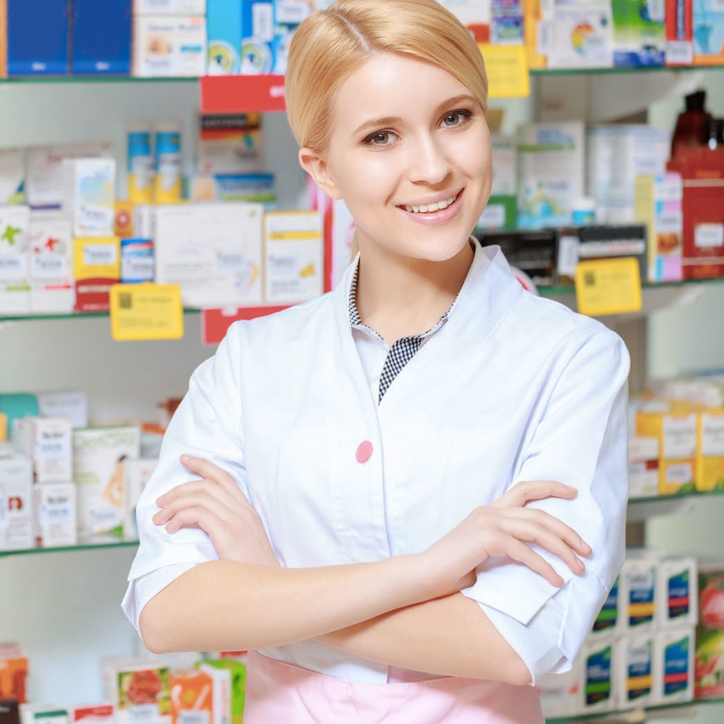 38305442 - everything for the best therapy. young smiling druggist in white uniform standing with her arms crossed near the show case of a drug store